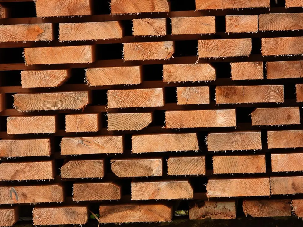 Madera de construcción aserrada y apilada, vista por las cabezas de las piezas